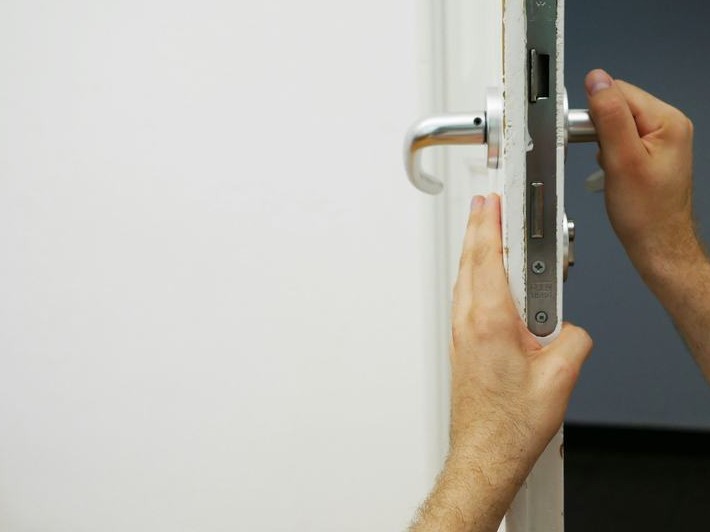 Handwerker montiert ein Türschloss an einer Wohnungstür